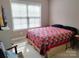 Bright bedroom featuring a colorful quilt, a large window, and neutral wall color at 810 Wynnshire Dr # D, Hickory, NC 28601