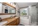 Bright bathroom featuring double vanity, soaking tub with window view, and glass-enclosed shower at 9131 Strattonville Ct, Huntersville, NC 28078