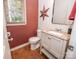 Cozy powder room with rust-colored walls, white vanity with a pink marble countertop, and unique star decor at 9131 Strattonville Ct, Huntersville, NC 28078