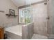 Glass-enclosed shower with neutral tile and a soaking tub below a window at 9131 Strattonville Ct, Huntersville, NC 28078