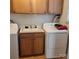 Well-equipped laundry room with a washer, dryer, utility sink, and wooden cabinets at 1033 College Ave, Shelby, NC 28152