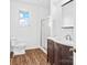 Bathroom featuring a toilet, shower with glass door, wood-look floors, and vanity with a dark wooden finish at 1111 W 4Th Ave, Gastonia, NC 28052