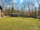 Large backyard offering green space for outdoor activities and a storage building for convenience at 1200 Carey Ct, Charlotte, NC 28210