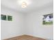 White bedroom showcasing hardwood floors, two windows, and ample natural light at 1200 Carey Ct, Charlotte, NC 28210