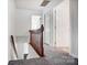 Upstairs hallway with carpet and wooden railing and three open doors at 130 Water Oak Dr, Pineville, NC 28134