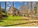 View of a brick home's backyard featuring a well-manicured lawn, a wooded area, and a screened-in porch at 1347 Lightwood Dr, Matthews, NC 28105