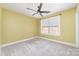 Bedroom featuring neutral carpet, yellow painted walls, white trim, and a ceiling fan with lights at 1347 Lightwood Dr, Matthews, NC 28105