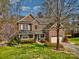 Two-story brick home with a manicured lawn, mature trees, and a front porch leading to a two-car garage at 1347 Lightwood Dr, Matthews, NC 28105