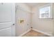 Functional laundry room with tile flooring, storage rack, and natural light from the window at 1347 Lightwood Dr, Matthews, NC 28105