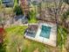 Aerial view of a community pool covered with a tarp, next to a tennis court and pool house at 1347 Lightwood Dr, Matthews, NC 28105