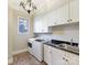 Functional laundry room with white cabinets, granite countertops, stainless steel sink, and modern appliances at 1355 Wyndmere Hills Ln, Matthews, NC 28105