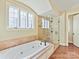 Bright main bathroom featuring a soaking tub, glass shower, and window at 1355 Wyndmere Hills Ln, Matthews, NC 28105