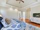 Comfortable main bedroom featuring a trey ceiling, ceiling fan, wood floors, and a media console at 1355 Wyndmere Hills Ln, Matthews, NC 28105