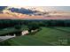 Scenic aerial view of the lush green golf course with a tranquil pond reflecting the sunset sky at 17201 Royal Court Dr, Davidson, NC 28036