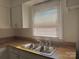 Sunlit kitchen sink with stainless steel basin and wood countertop, brightened by a window view at 2210 Milton Rd, Charlotte, NC 28215