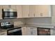 Close up of updated kitchen with new stainless steel appliances, white cabinets, and gray backsplash at 2400 Pressley Rd, Chester, SC 29712