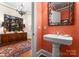 Stylish powder room featuring a pedestal sink, decorative mirror, and unique coral-painted walls at 2823 Providence Rd # 156, Charlotte, NC 28211