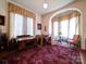 Living room with a red rug, curtains, wooden desk, and neutral walls at 303 Wade St, Wadesboro, NC 28170