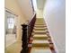 Carpeted staircase with a dark wood banister and bright lighting at 303 Wade St, Wadesboro, NC 28170