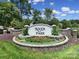 An inviting neighborhood entrance featuring a stone-lined 'River Park' sign with lush green landscaping and bright sunny skies at 325 Ox Bow Cir, Mount Holly, NC 28120