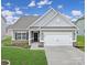 Charming single-Gathering home featuring a two-car garage and a well-manicured lawn under a bright, cloudy sky at 325 Ox Bow Cir, Mount Holly, NC 28120