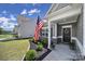 Inviting front porch with American flag, decorative plants, and well-maintained landscaping enhances curb appeal at 325 Ox Bow Cir, Mount Holly, NC 28120