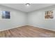 Bedroom featuring neutral walls, wood-look flooring, white trim, and two windows offering a tree-lined view at 325 Spring Oak Dr, Salisbury, NC 28147