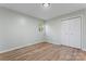 Bedroom featuring neutral walls, wood-look flooring, closet with sliding doors, white trim, and tree-lined view at 325 Spring Oak Dr, Salisbury, NC 28147