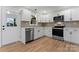 Well-lit kitchen with stainless steel appliances, white cabinets, hard-wood flooring, and gray subway tile backsplash at 325 Spring Oak Dr, Salisbury, NC 28147