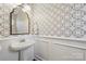 Elegant powder room with decorative mirror, pedestal sink, and patterned wallpaper at 4811 Dawnridge Dr, Charlotte, NC 28226