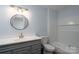 Bathroom with gray vanity, round mirror, updated fixtures, and shower-tub combo at 6415 Santa Cruz Trl # 11, Charlotte, NC 28227