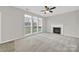 Bright living room features large windows, neutral carpet, ceiling fan, and a fireplace at 8620 Grey Squirrel Ct, Charlotte, NC 28277