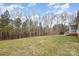 Large backyard with tall trees and a staircase to a covered back porch overlooking the grassy lawn at 1165 Golden Maple Ln, Chester, SC 29706