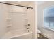 Bright bathroom featuring a shower-tub combo with black fixtures and built-in shelving for storage at 117 Mountain View St, Gastonia, NC 28052