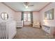 Bright bedroom features pastel pink accents, a ceiling fan, and two bassinets at 130 N Smallwood Pl, Charlotte, NC 28216