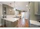 This kitchen features a stainless steel sink, muted green cabinets, wooden floors and quartz countertops at 130 N Smallwood Pl, Charlotte, NC 28216
