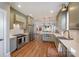 This kitchen features stainless steel appliances, muted green cabinets, wooden floors and open access to the living room at 130 N Smallwood Pl, Charlotte, NC 28216