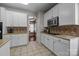 Well-lit kitchen with white cabinetry, tile backsplash, stainless steel microwave, and tile flooring at 1668 Onyx Rdg # 116, Fort Mill, SC 29708