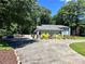 Well-maintained exterior with mature trees, a spacious driveway, and lush landscaping at 18 Pickett Ave, Spencer, NC 28159
