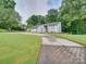 Well-maintained front yard with a circular driveway, mature trees, and manicured landscaping at 18 Pickett Ave, Spencer, NC 28159