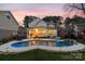 Stunning backyard at dusk with inground pool, lush landscaping, and a cozy patio area at 20601 Island Forest Dr, Cornelius, NC 28031