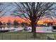 Picturesque lake view at sunset featuring a canopy-covered boat lift and vibrant orange sky at 20601 Island Forest Dr, Cornelius, NC 28031