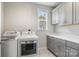Bright laundry room with gray cabinets, white countertop, sink, and modern washer and dryer at 20601 Island Forest Dr, Cornelius, NC 28031