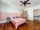 Charming bedroom boasts hardwood floors, pink accent wall, ceiling fan and playful decorative touches at 225 Marion St, Rock Hill, SC 29730
