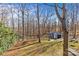 View of backyard with shed and fire pit surrounded by a wooded landscape at 2913 Archdale Dr, Charlotte, NC 28210