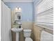 Bathroom with pedestal sink, light blue walls, and natural lighting from a large window at 2913 Archdale Dr, Charlotte, NC 28210