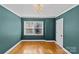 Empty bedroom with teal walls, gleaming hardwood floors, large windows, and a modern light fixture at 2913 Archdale Dr, Charlotte, NC 28210