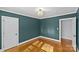 Empty bedroom with teal walls, gleaming hardwood floors, large windows, and a modern light fixture at 2913 Archdale Dr, Charlotte, NC 28210