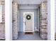 Close-up of the front door showcasing stone columns, stylish wreath, and a welcome mat, creating a charming entrance at 527 Morrows Turnout Way, Pineville, NC 28134