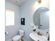 Well-lit half bathroom featuring a modern round mirror, pedestal sink with gold fixtures, and neutral wall color at 527 Morrows Turnout Way, Pineville, NC 28134